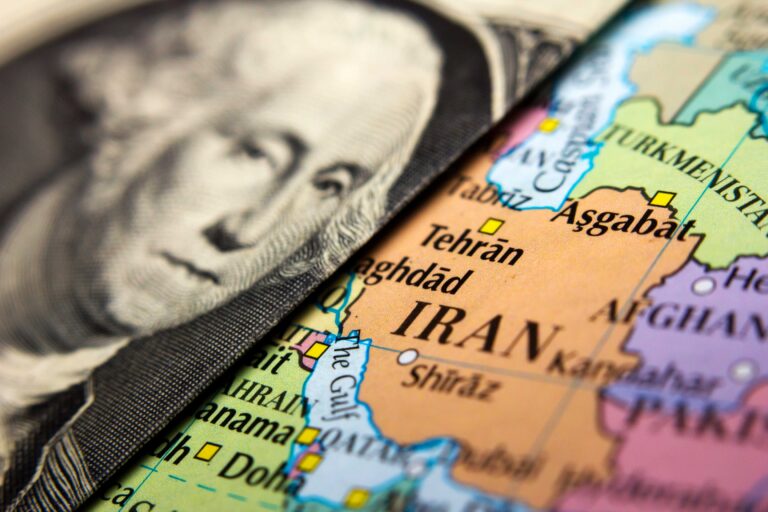 Dollar bill laid over map of Iraq and Iran.