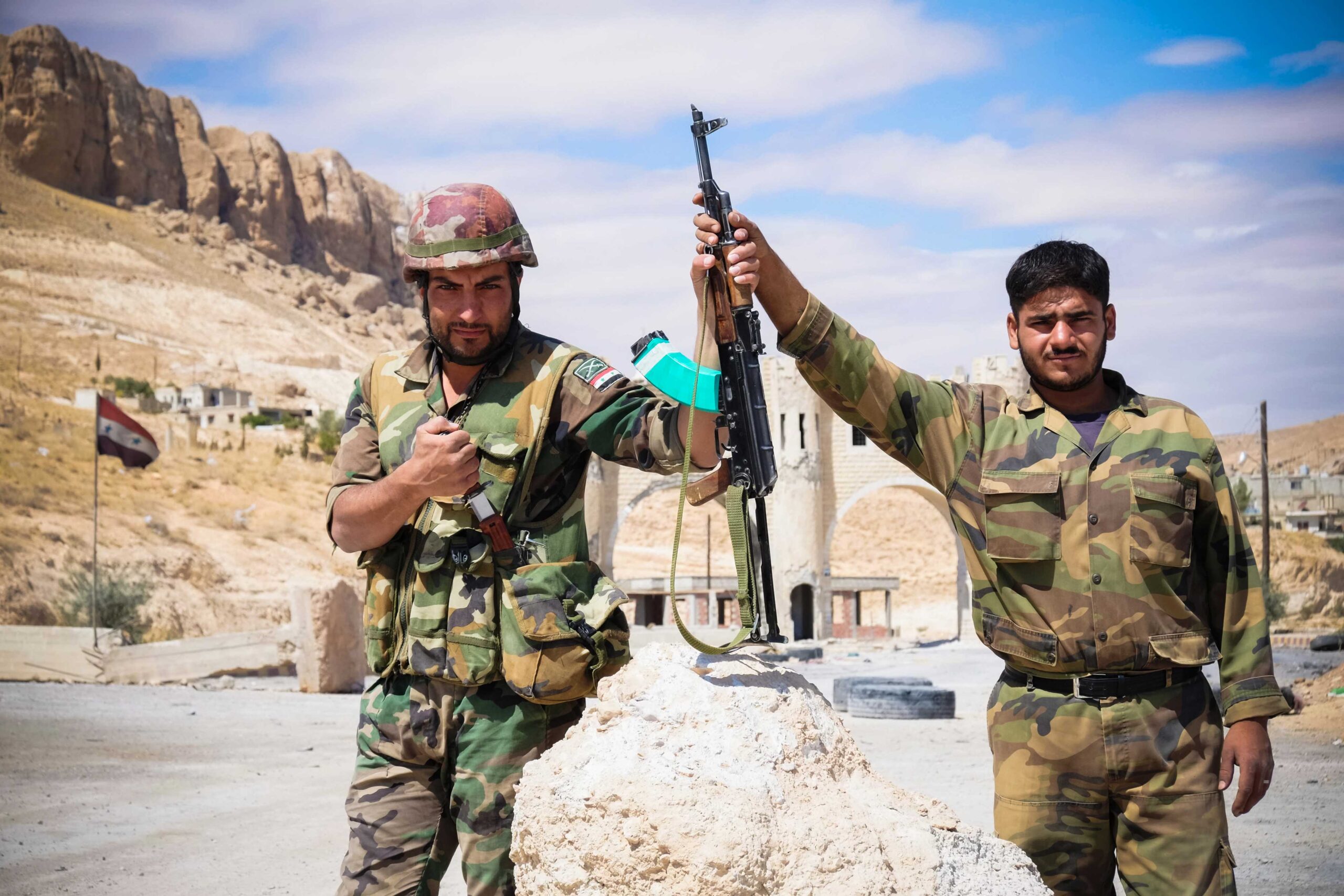 Two soldiers of Syria's National army holding up a rifle.