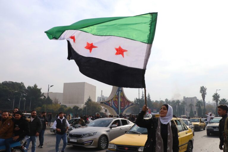 Woman waving new green Syrian flag after the fall of Bashar al-Assad in Syria.