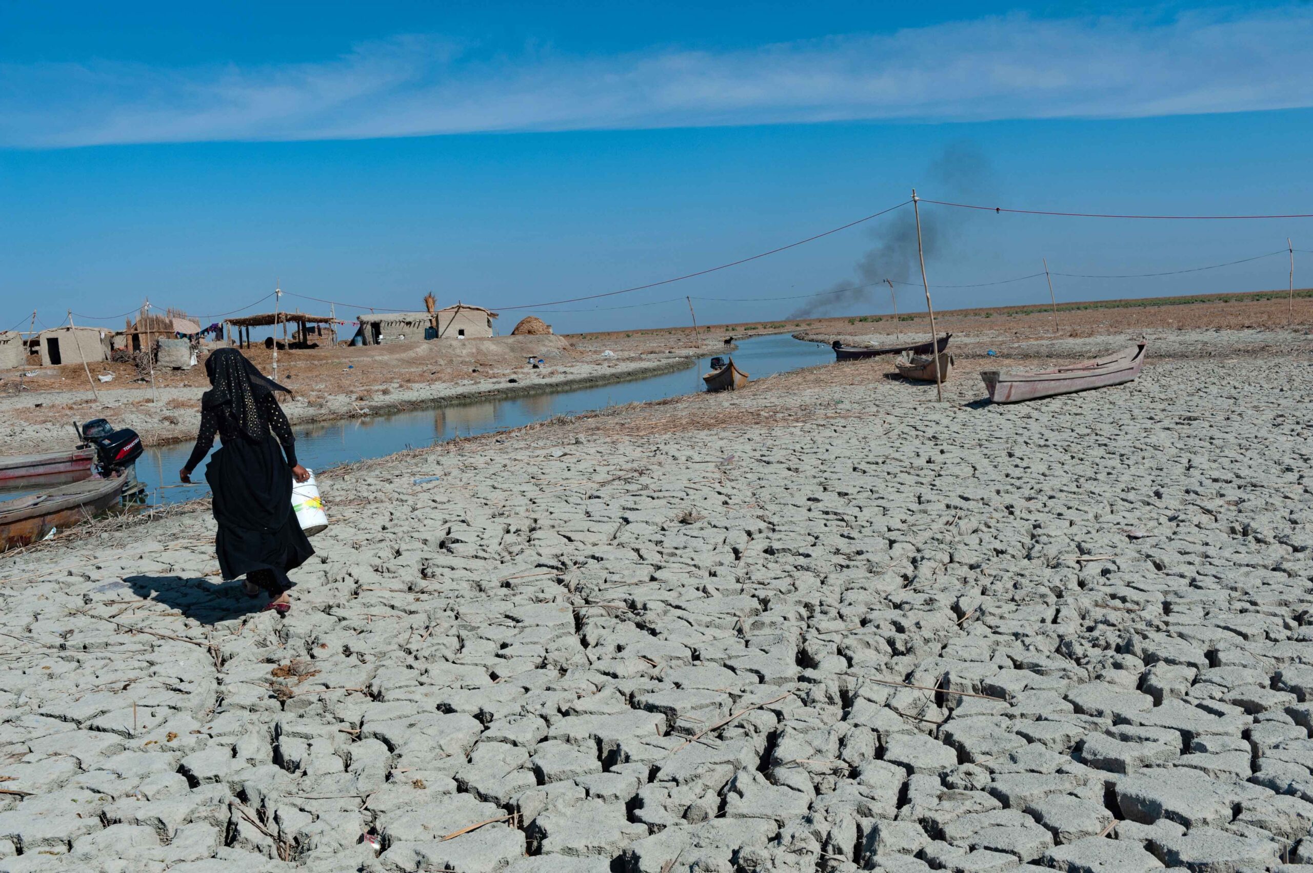 Arid climate in the Middle East, drought, woman walking across field.