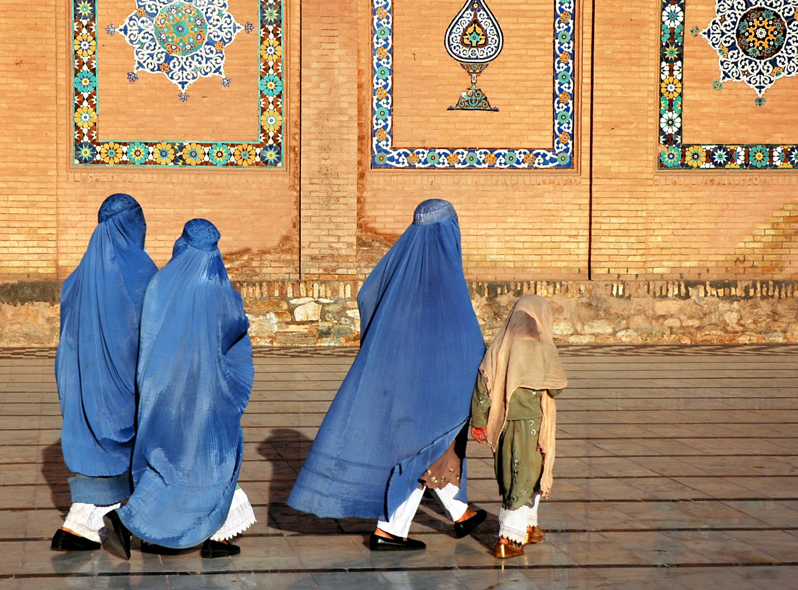 Herat in western Afghanistan. The Great Mosque of Herat (Friday Mosque or Jama Masjid). Three women in burqas and a girl walk at the front of the mosque. The mosque is one of the oldest in Afghanistan