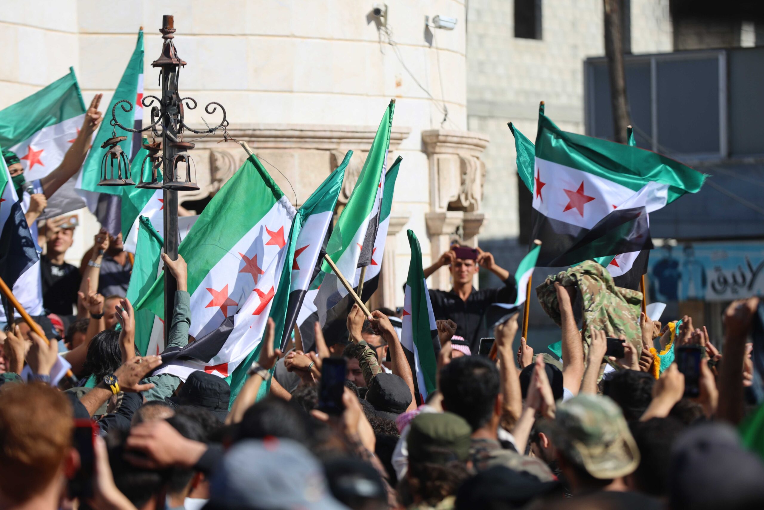 People in Syria waving the country's new flag after the fall of Bashar al-Assad.