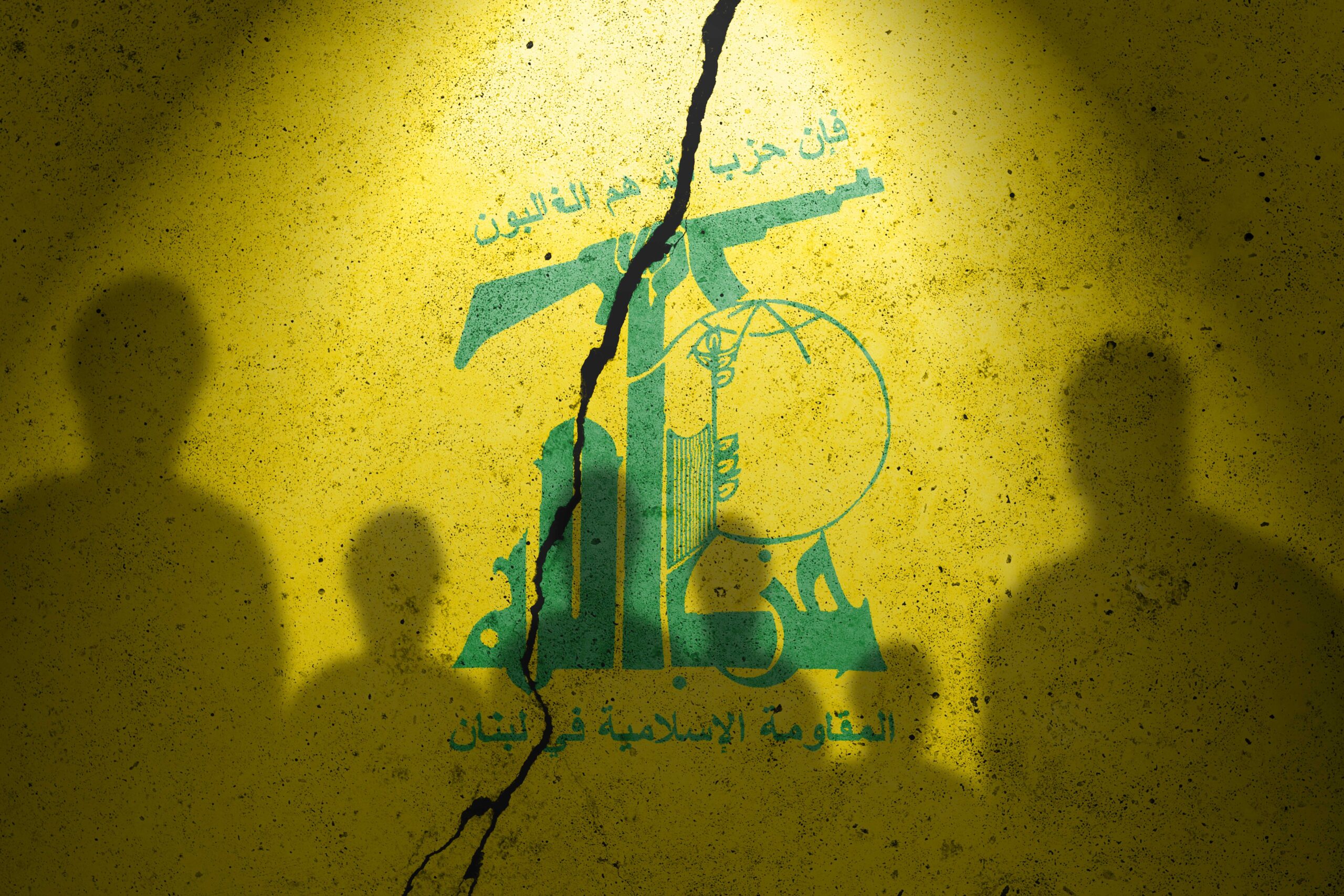 Flag of terrorist organization Hezbollah painted on the concrete wall with humans shadows. Terrorist organization Hezbollah.