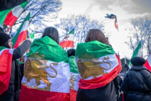 Members of the Iranian diaspora gathered with placards and chanted slogans, carrying historical Iranian flags featuring the Lion and Sun symbol, and expressed support for Reza Pahlavi.