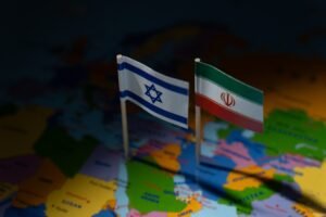Miniature flags of Israel and Iran on a blurred map. International relations, conflict, diplomacy, and geographical focus on the Middle East concept.