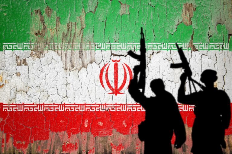 Flag of Iran painted on the cracked wall with terrorist shadow.