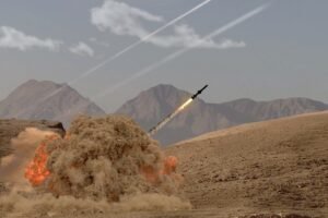 The rocket soars into the sky, leaving behind a trail of smoke in the desert in the middle of the mountains.